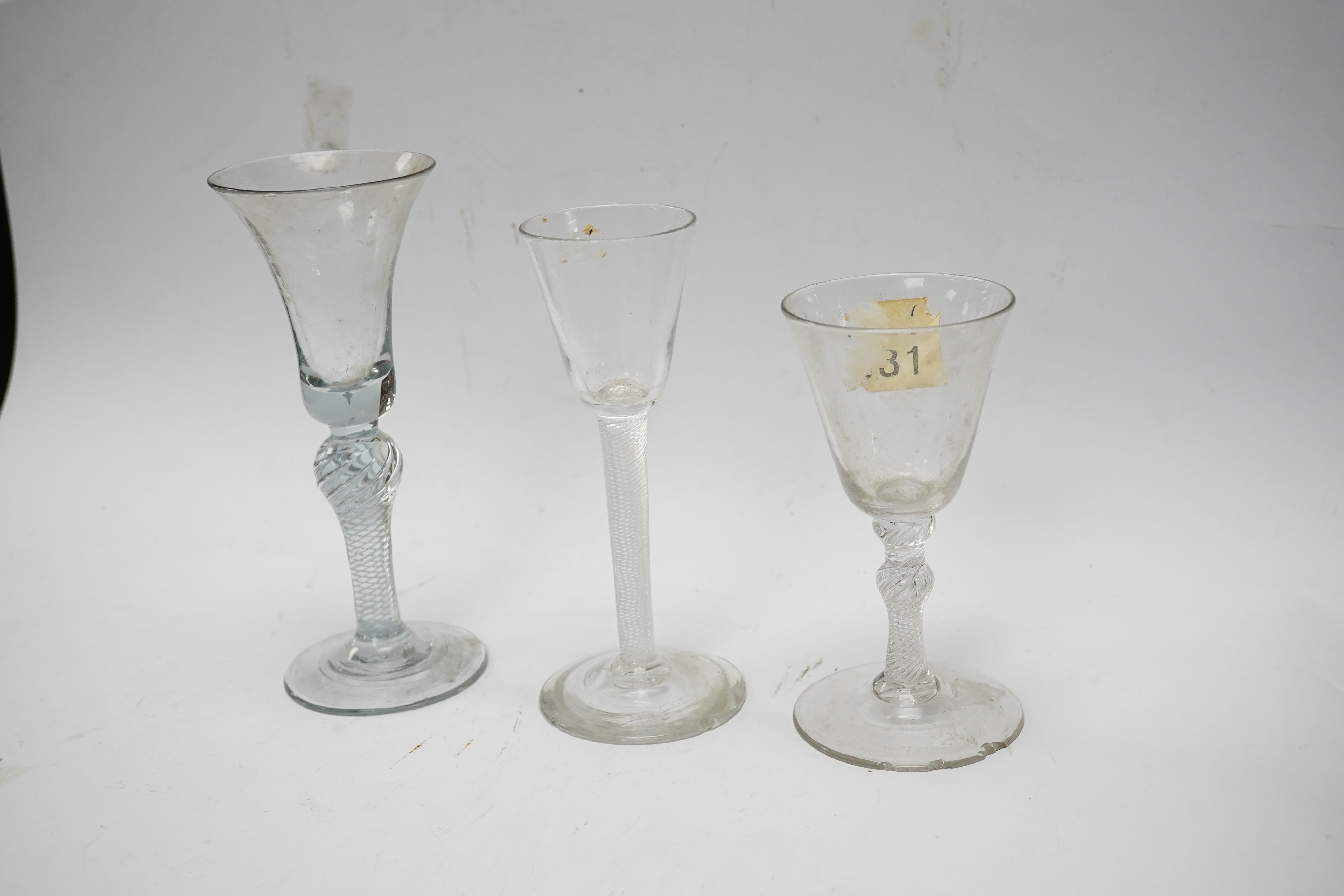 Three 18th century air twist stemmed wine glasses, tallest 16.5cm high. Condition - two having chips to edges of bases